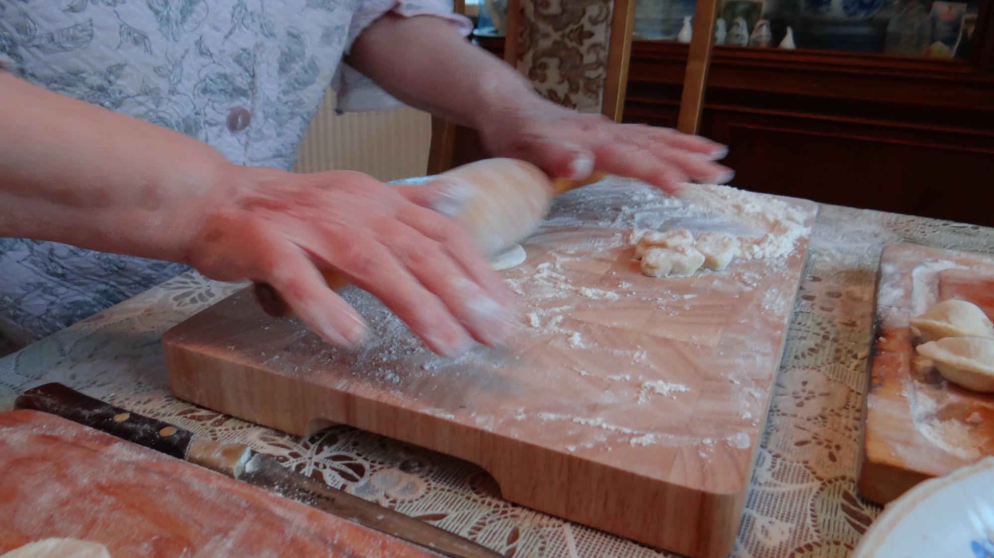 Hands kneading dough on wooden board